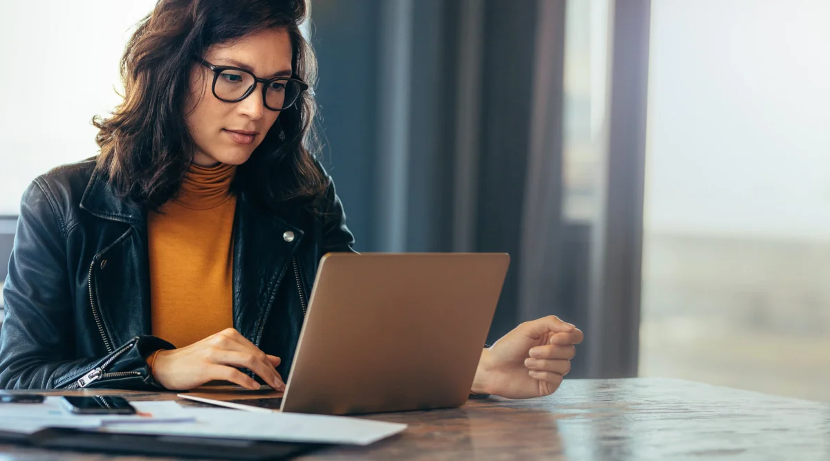 Woman in a leather jacket focused on a laptop